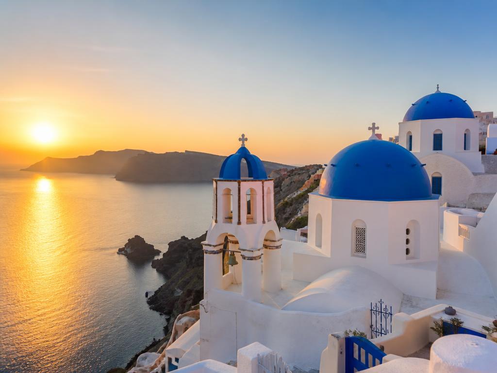 Santorini white buildings with blue domes overlooking the caldera at sunset